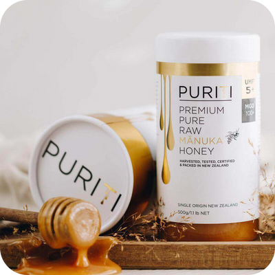 novita SG's PURITI Premium Raw Manuka Honey UMF 5+ | MGO 100 on a wooden tray.