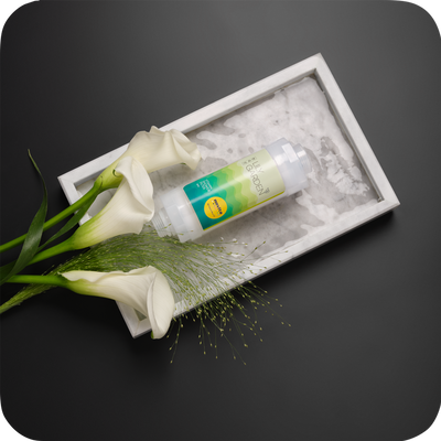A bottle of novita SG Vitamin Shower Filter on a tray with lilies.