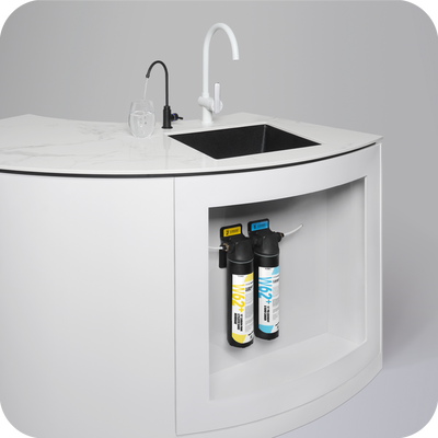 A white kitchen with a sink and a 15” Undersink Filtration System W62 Plus– The Home • Ultra bottle of water by novita.