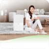 A woman sitting on the floor next to a novita Dehumidifier ND12 Twin Pack.