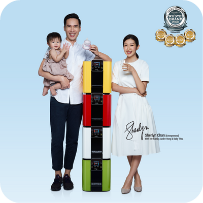 A family is posing for a photo in front of a stack of novita HydroCube™ Hot/Cold Water Dispensers W29 with 3 Years Warranty, showcasing the product's size and variety.