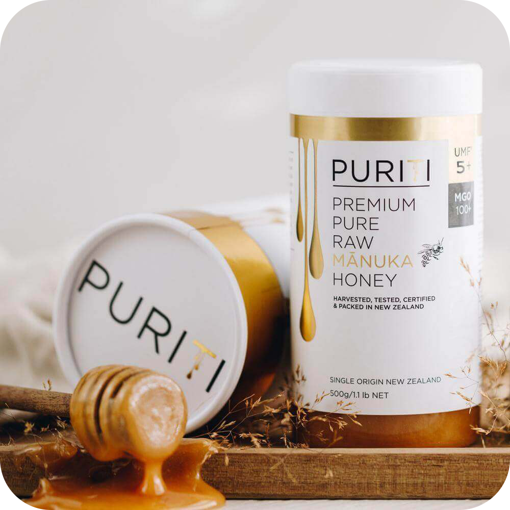 novita SG's PURITI Premium Raw Manuka Honey UMF 5+ | MGO 100 on a wooden tray.