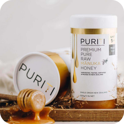 Novita SG presents PWP Offer: PURITI Premium Raw Manuka Honey UMF 5+ | MGO 100 on a wooden tray.